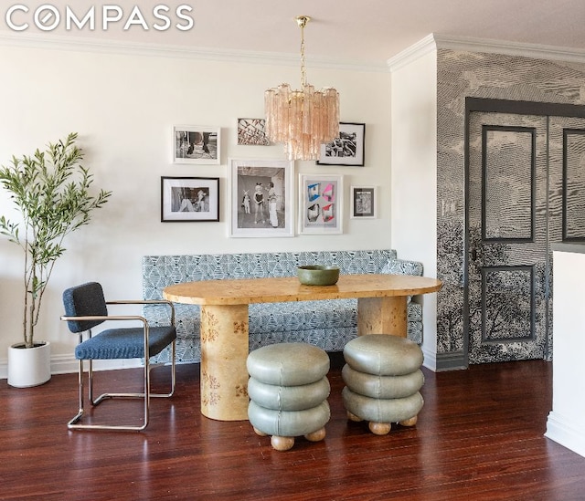 dining space featuring dark wood-type flooring, ornamental molding, and a notable chandelier