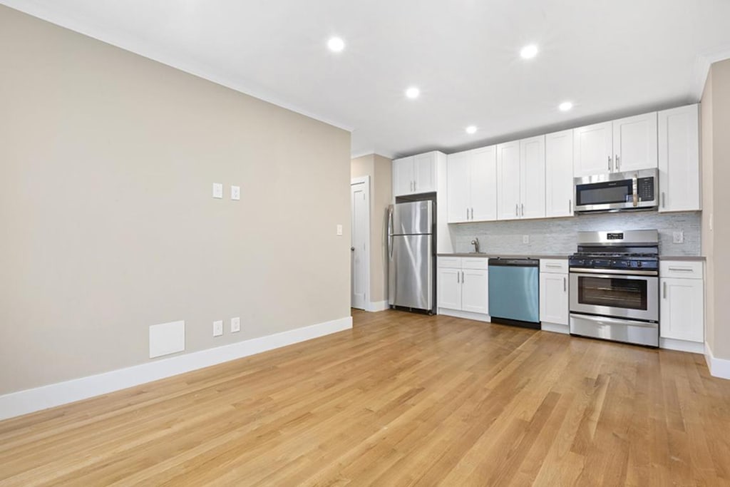 kitchen with appliances with stainless steel finishes, white cabinets, and tasteful backsplash