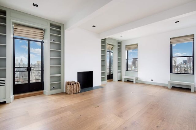 unfurnished living room featuring built in features, wood finished floors, baseboards, french doors, and beamed ceiling