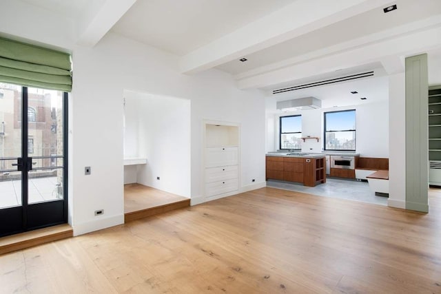 unfurnished bedroom featuring light wood finished floors, beamed ceiling, french doors, and baseboards