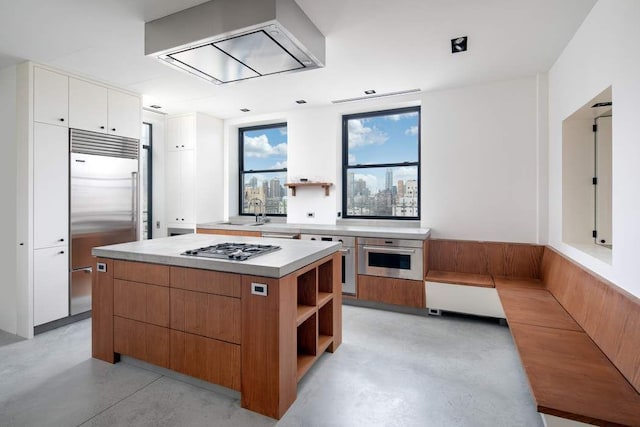 kitchen featuring open shelves, finished concrete floors, light countertops, appliances with stainless steel finishes, and white cabinetry