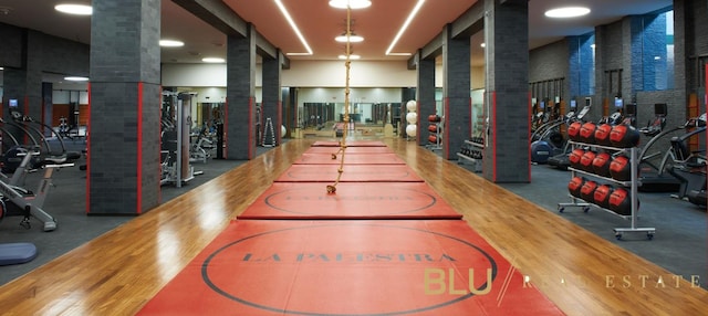 exercise room with hardwood / wood-style flooring and decorative columns