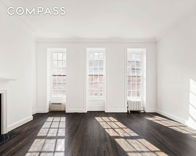 empty room featuring plenty of natural light, crown molding, radiator heating unit, and dark wood-style flooring