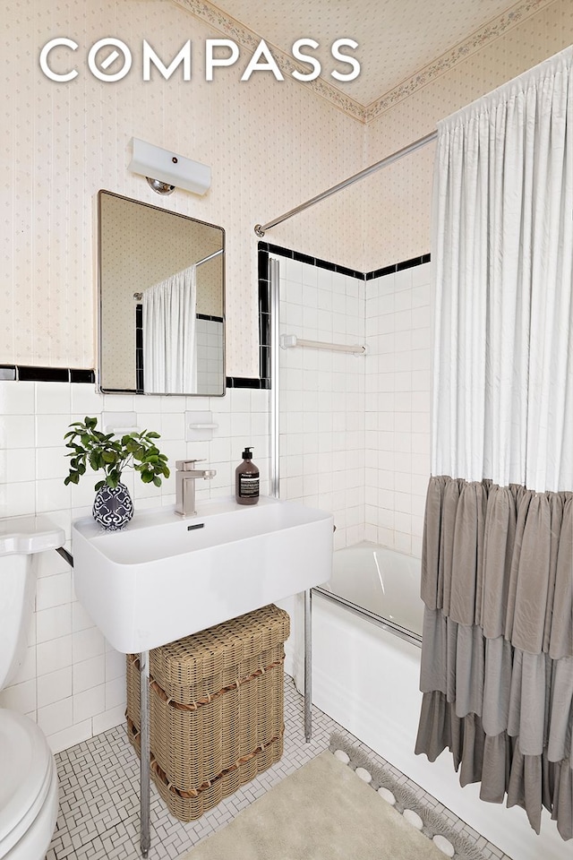 bathroom with wallpapered walls, shower / bath combination with curtain, tile walls, and tile patterned floors