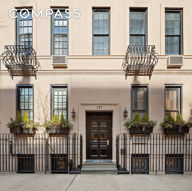 view of exterior entry featuring fence and stucco siding