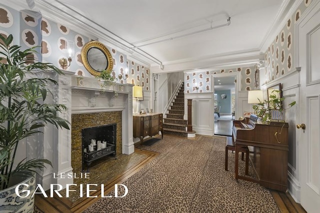 living room featuring wainscoting, stairway, crown molding, a decorative wall, and a high end fireplace