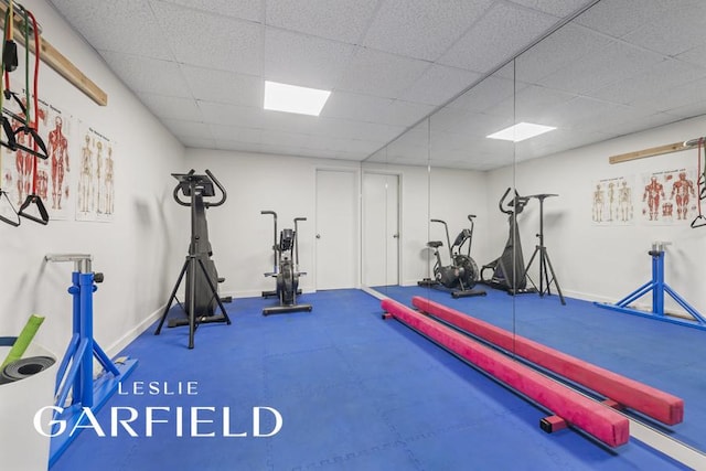 exercise room with a drop ceiling and baseboards