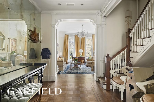 entryway featuring visible vents, stairway, ornamental molding, an inviting chandelier, and ornate columns