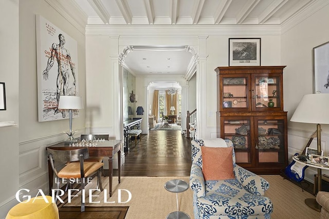 corridor featuring crown molding, wood finished floors, decorative columns, and a decorative wall