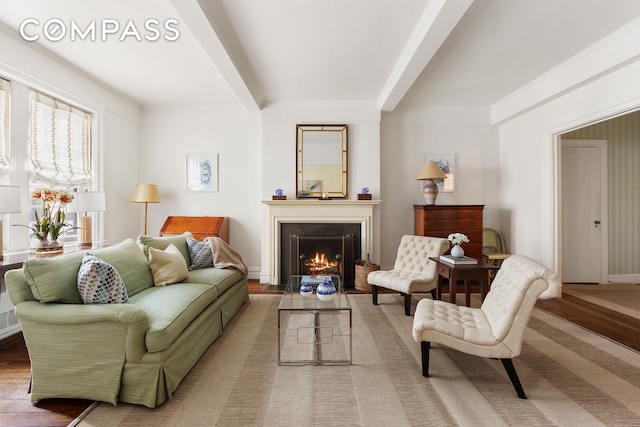 sitting room with a fireplace with flush hearth, beamed ceiling, baseboards, and wood finished floors