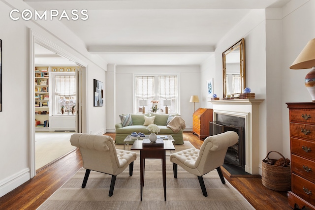 living room featuring dark wood-type flooring, a fireplace, baseboards, and beam ceiling