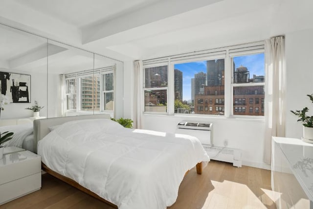 bedroom with multiple windows, hardwood / wood-style floors, and baseboard heating