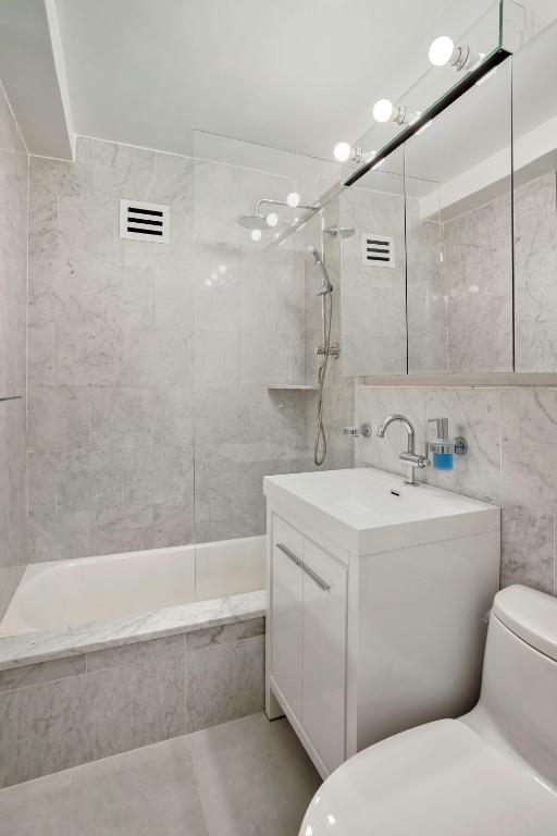 full bathroom featuring tiled shower / bath, tile walls, vanity, and toilet