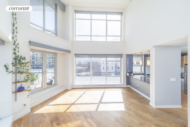 unfurnished living room with a high ceiling, hardwood / wood-style floors, and plenty of natural light