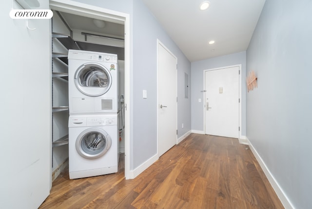 washroom with dark wood-type flooring, electric panel, and stacked washer / drying machine