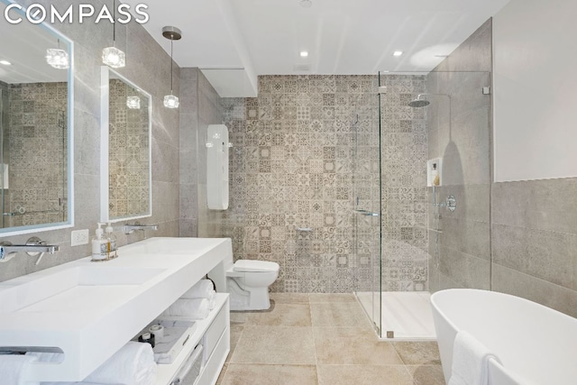 full bathroom with toilet, shower with separate bathtub, tile walls, and vanity