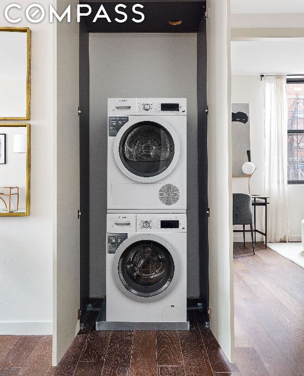 laundry area with stacked washer / dryer and hardwood / wood-style flooring