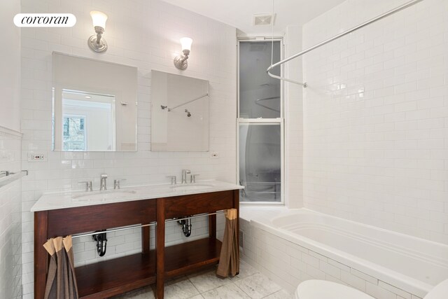 full bathroom with tile patterned floors, tile walls, tiled shower / bath combo, and toilet