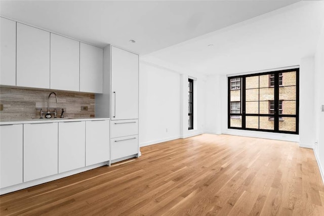 unfurnished living room featuring sink and light hardwood / wood-style flooring