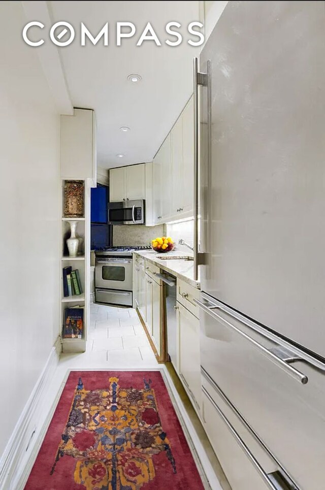 bedroom featuring light wood finished floors, baseboards, and beam ceiling