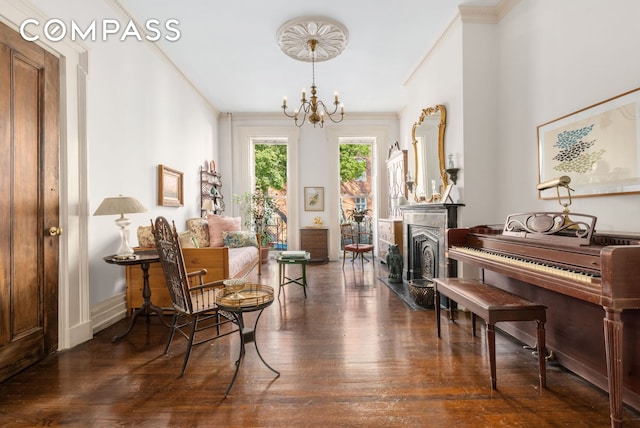 living area featuring a notable chandelier, baseboards, dark wood finished floors, and crown molding