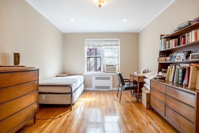 bedroom featuring cooling unit, radiator, and light wood-type flooring