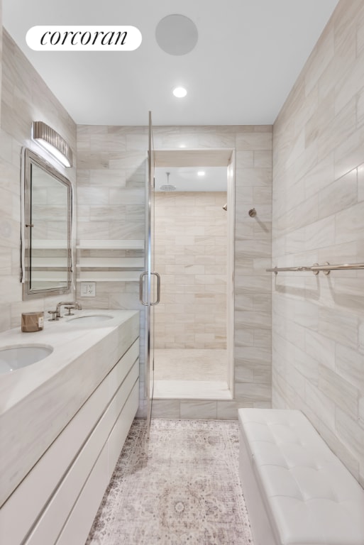 bathroom with vanity, a shower with door, and tile walls