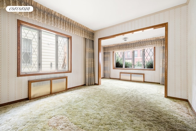 carpeted empty room featuring baseboards and wallpapered walls