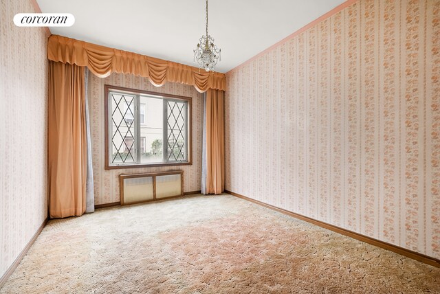 empty room featuring carpet floors and a notable chandelier