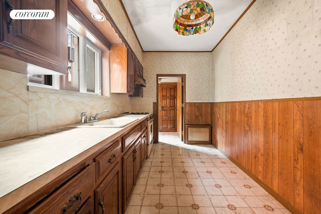 interior space with tile patterned floors, wallpapered walls, wood walls, crown molding, and wainscoting