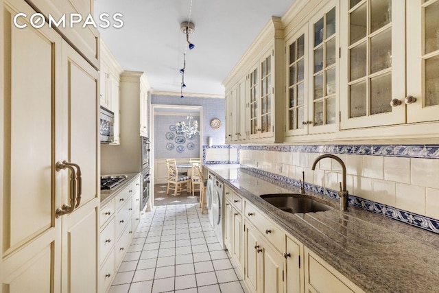 kitchen with pendant lighting, sink, dark stone countertops, stainless steel appliances, and cream cabinets