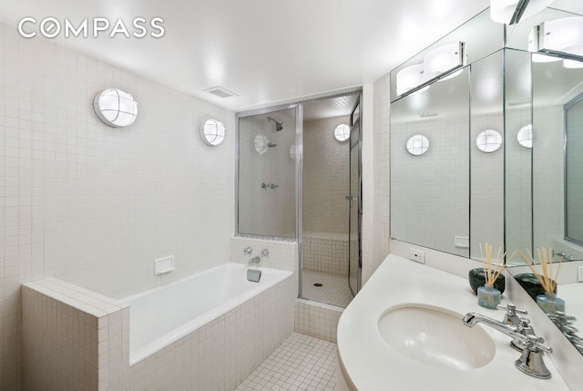 bathroom featuring plus walk in shower, tile walls, and vanity