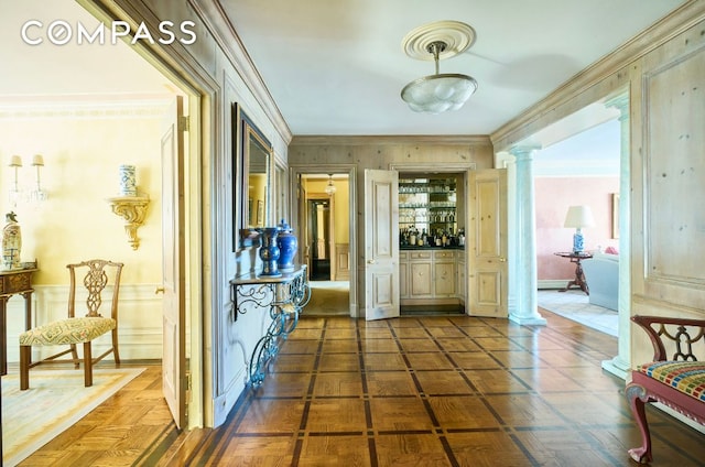 hall with crown molding, decorative columns, and dark parquet floors