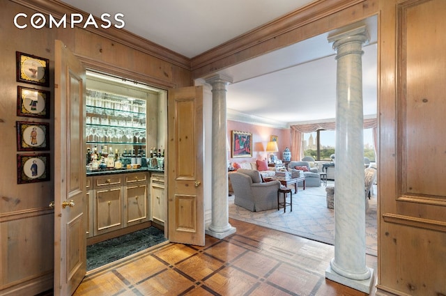 entrance foyer with bar, crown molding, and decorative columns