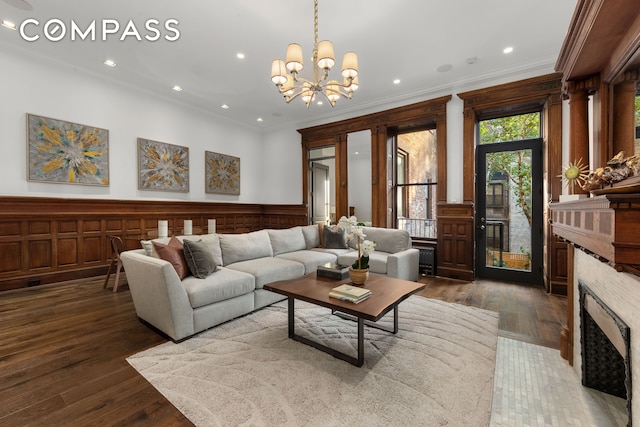 living area with wood finished floors, a fireplace, a wainscoted wall, and ornamental molding