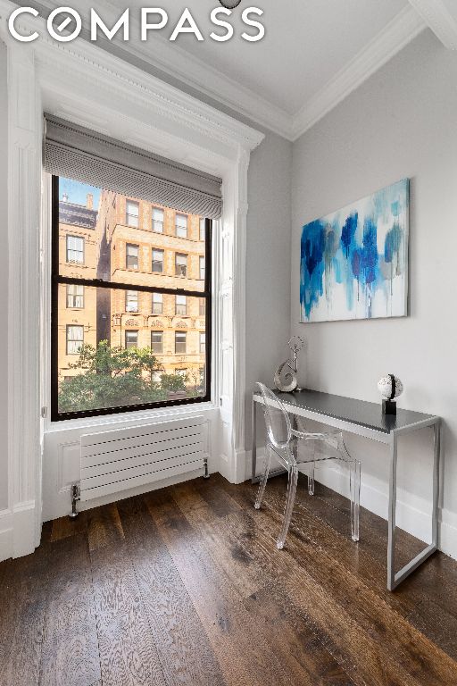 home office featuring dark wood-type flooring, radiator heating unit, and crown molding