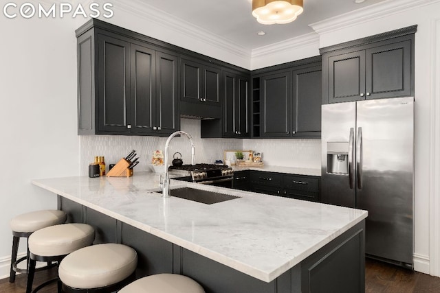 kitchen with a kitchen bar, decorative backsplash, sink, stainless steel fridge, and kitchen peninsula