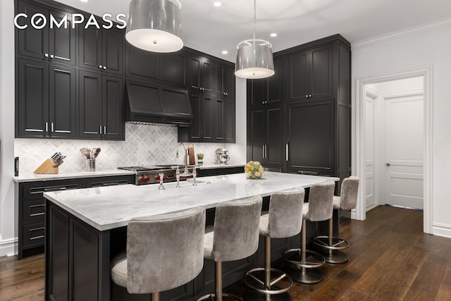 kitchen featuring dark wood-style floors, light stone countertops, custom range hood, tasteful backsplash, and ornamental molding