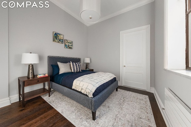 bedroom featuring dark hardwood / wood-style floors, radiator heating unit, and ornamental molding