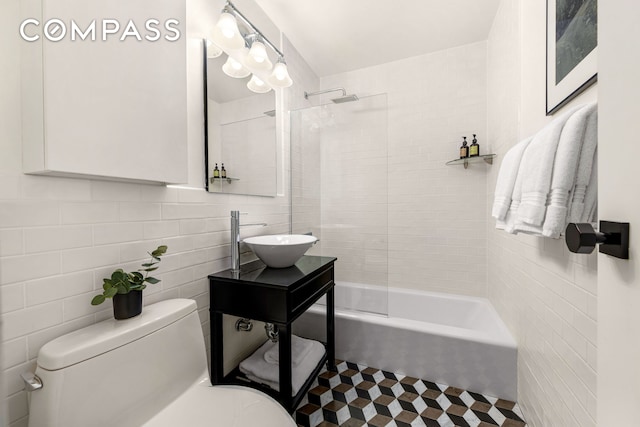 bathroom featuring a sink, shower / bathing tub combination, toilet, and tile walls