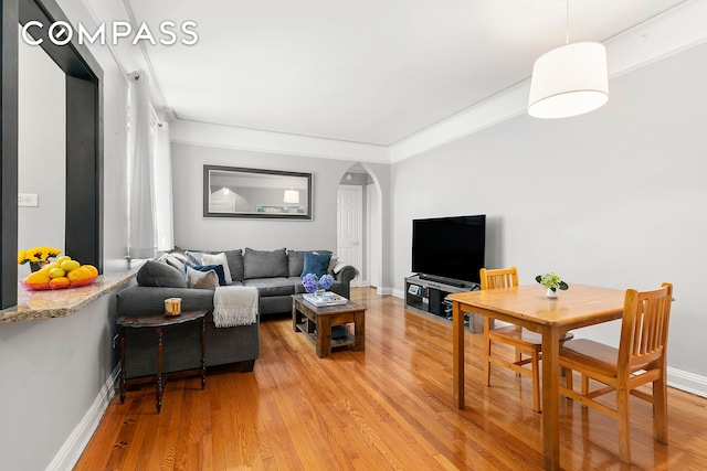 living area featuring arched walkways, baseboards, and light wood-style floors