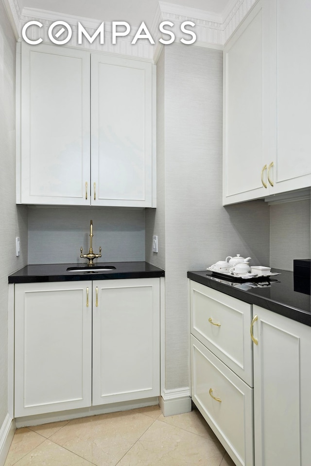 kitchen featuring dark countertops, white cabinets, and a sink