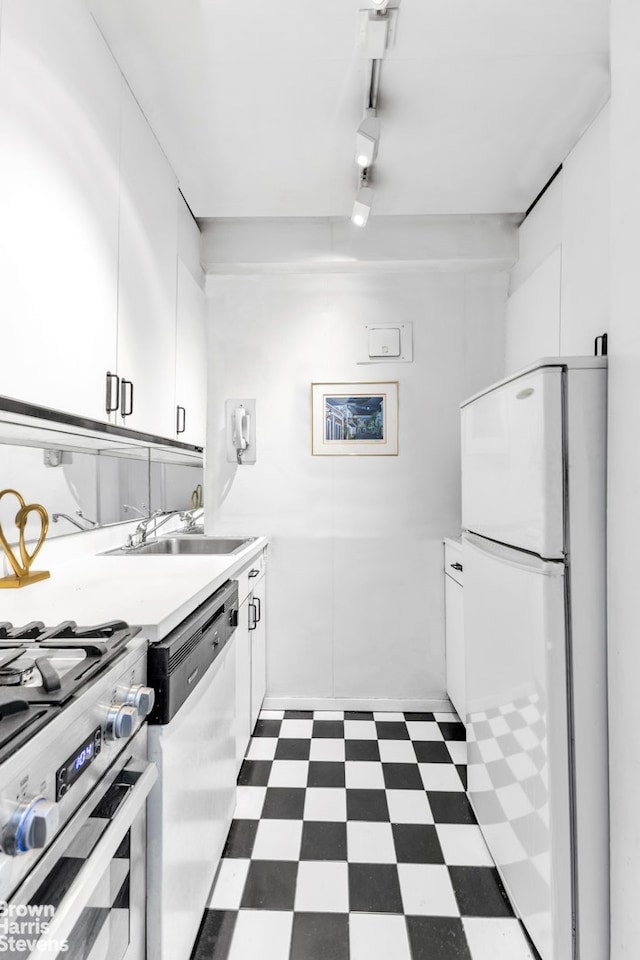 kitchen with appliances with stainless steel finishes, dark floors, white cabinets, and a sink