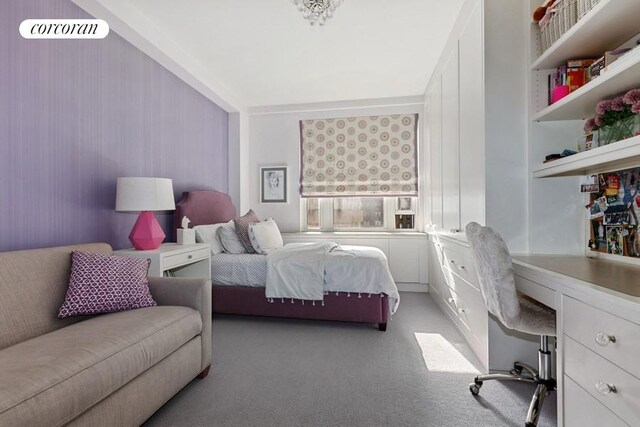 bedroom with light colored carpet and built in desk
