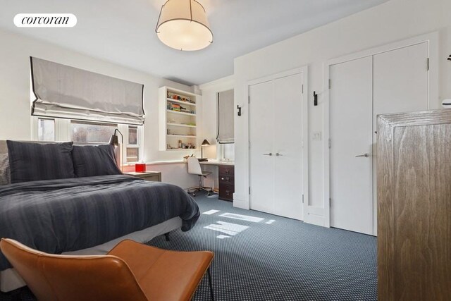 carpeted bedroom featuring visible vents and built in desk