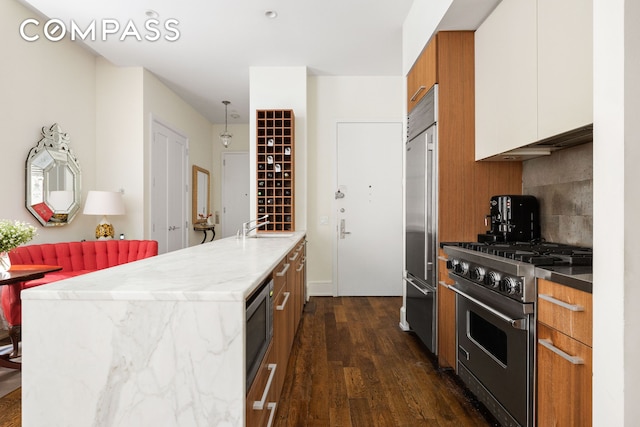 kitchen with brown cabinets, decorative backsplash, dark wood-type flooring, white cabinets, and built in appliances