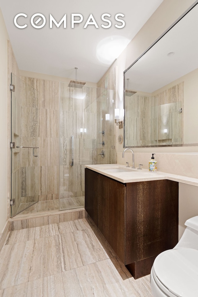 bathroom with toilet, a stall shower, and vanity