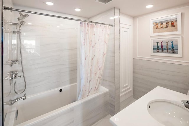 bathroom featuring sink, tile walls, and shower / bathtub combination with curtain