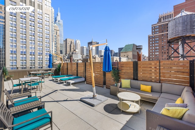 view of patio / terrace featuring fence, outdoor lounge area, and a city view