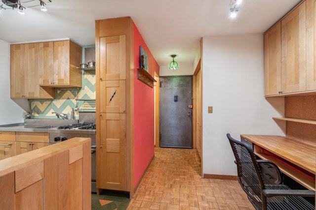 kitchen with light brown cabinets, high end stove, butcher block countertops, baseboards, and decorative backsplash